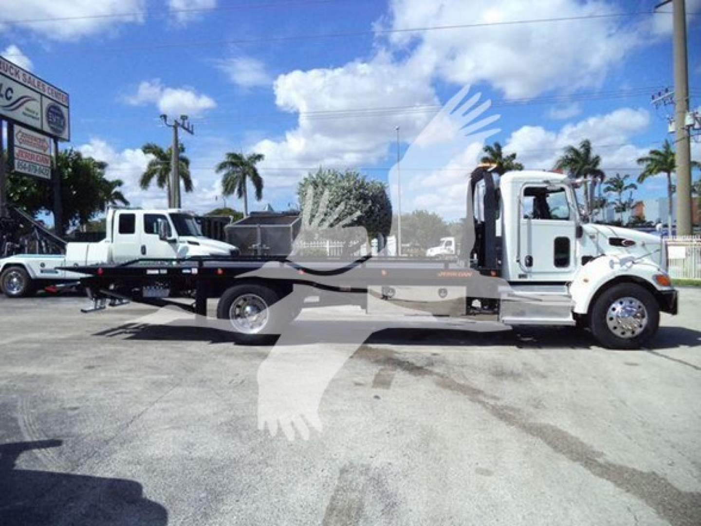 Peterbilt 337 rollback truck side view showing flatbed with white cab and gray chassis.