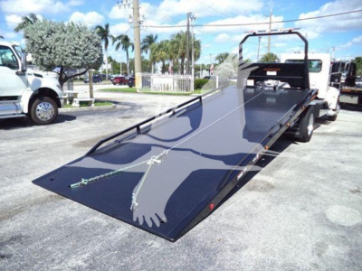 Truck bed with a lowered flatbed dollies and rear rollover ramp on a Peterbilt 337 rollback truck.