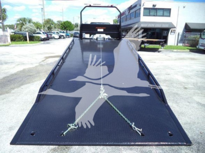 Peterbilt 337 rollback truck bed with hydraulic flatbed, chains secured, front cab visible in background.