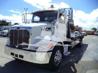Peterbilt 337 rollback tow truck in a used inventory photo, front grille, side deck, dual mirrors and chrome wheels visible.