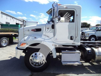 Peterbilt 337 rollback truck side view showing cab and front wheel, white exterior, chrome wheels, fuel tanks, and side steps.