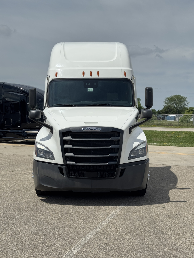 Front view of a white Freightliner Cascadia 126 semi truck with large black grille and bumper, in-service condition.