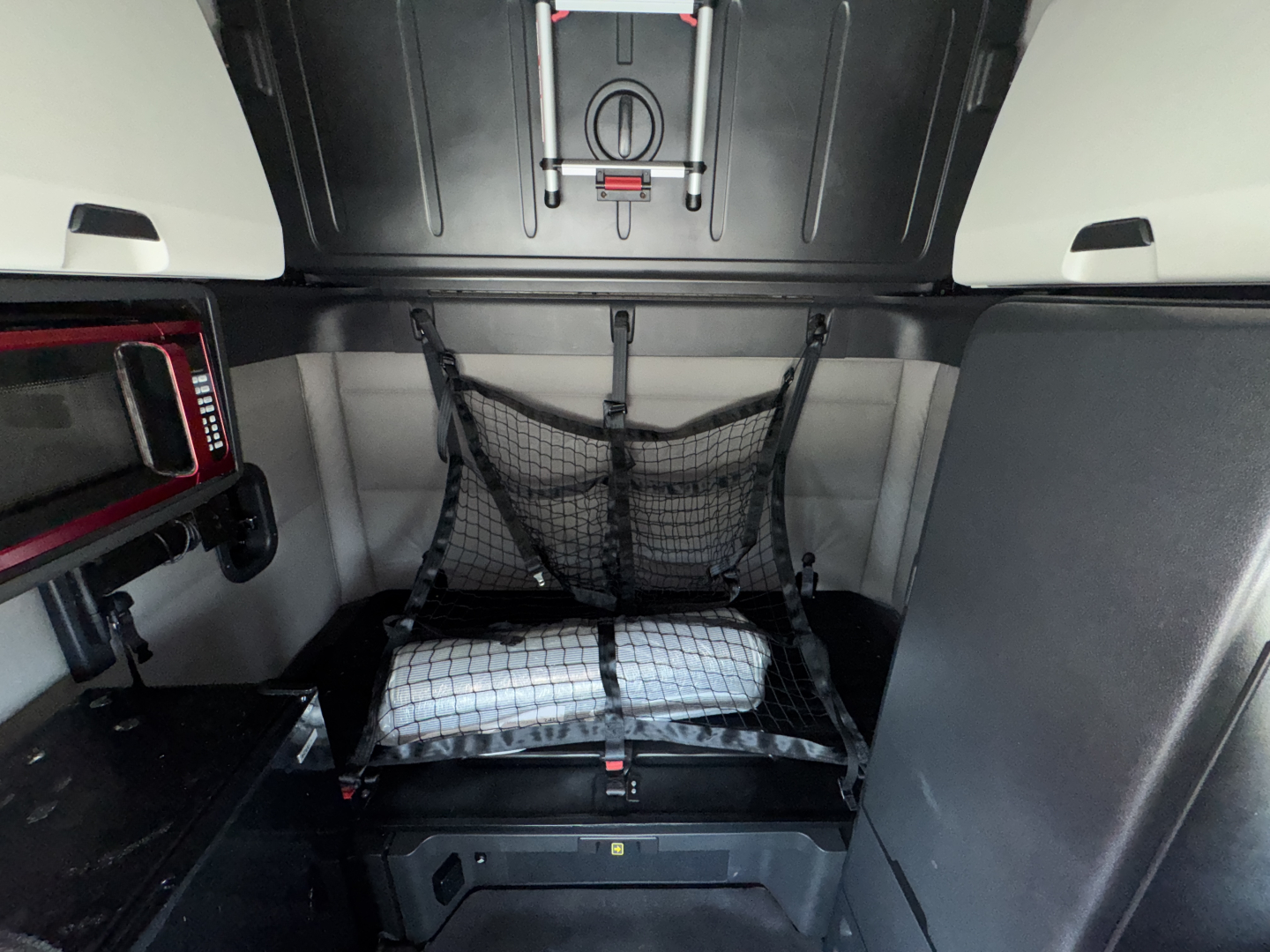 Freightliner Cascadia 126 sleeper cab interior cargo area with netted storage and fold-down bed in a compact rear compartment.