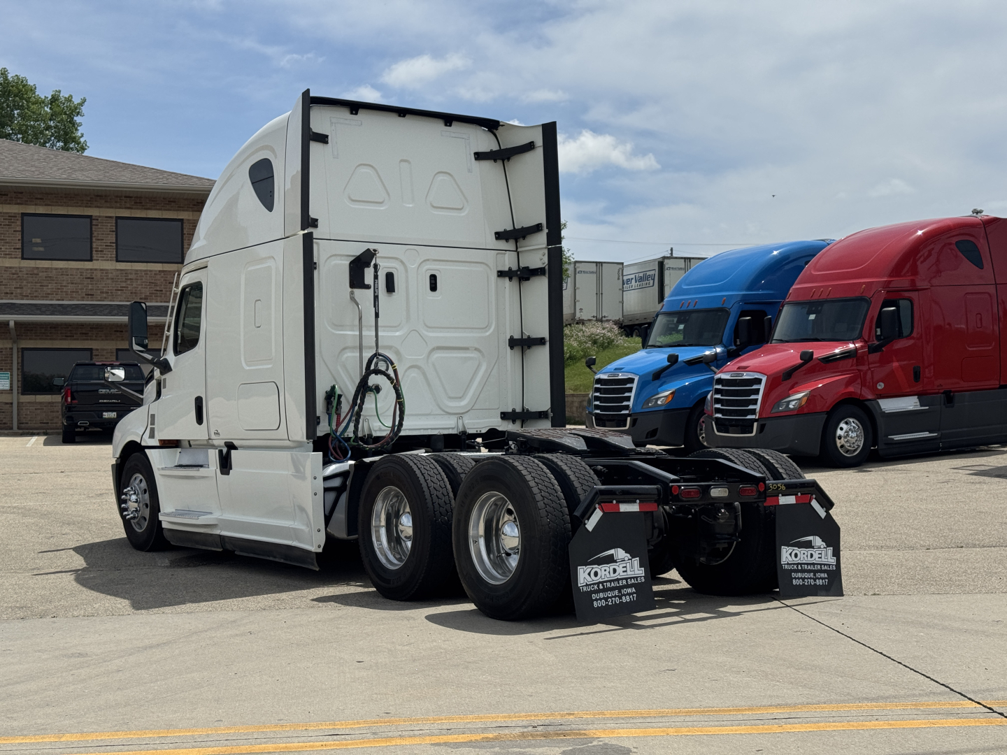 Truck chassis of a 2021 Freightliner Cascadia 126 rear view showing triple axle and fifth wheel with mud flaps.