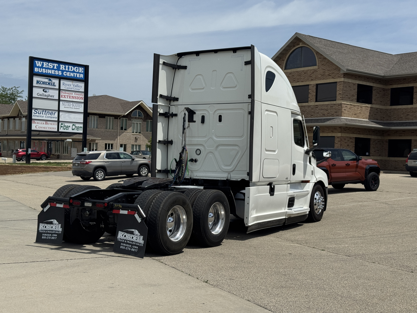 Truck tractor rear and cab side view showing fifth wheel and dual rear axles in a parking lot.