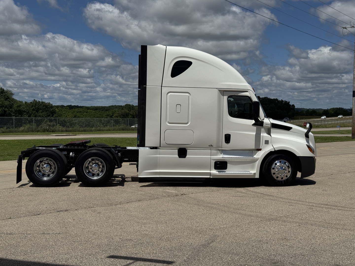 Freightliner Cascadia 126 sleeper tractor side profile with white paint and black chassis, visible wheels and trailer connection ports.