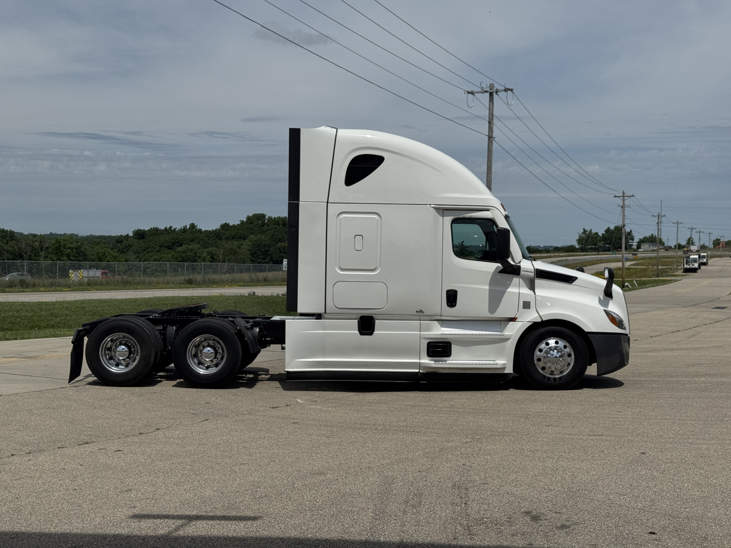 Truck side view of a white 2021 Freightliner Cascadia 126 tractor, sleeper cab, with a three-axle rear configuration visible.