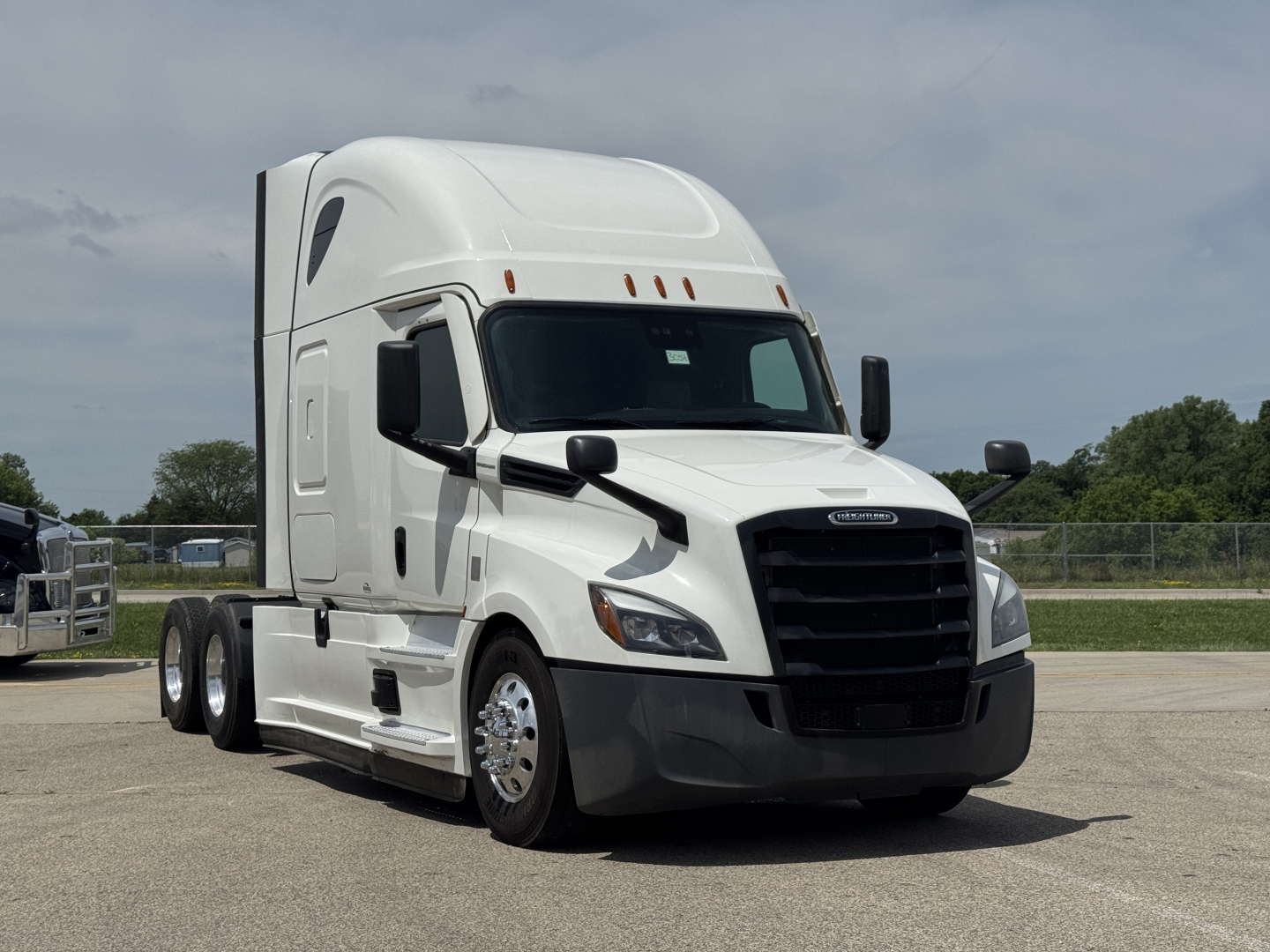 Truck: White Freightliner Cascadia 126 semi-truck over 3/4 view showing front grille, bumper, and cab with sleeper; no visible text legible on the body.