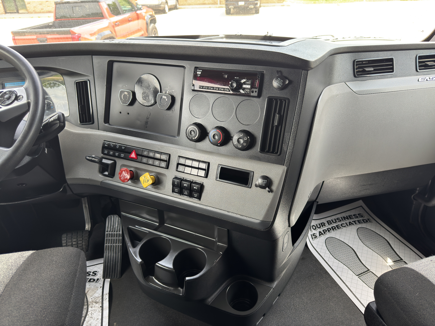 Truck dash of a Freightliner Cascadia sleeper showing instrument cluster, controls, and cup holders.