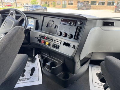 Dashboard view of a Freightliner Cascadia 126 cab showing steering wheel, instrument cluster, switches, and cup holders.