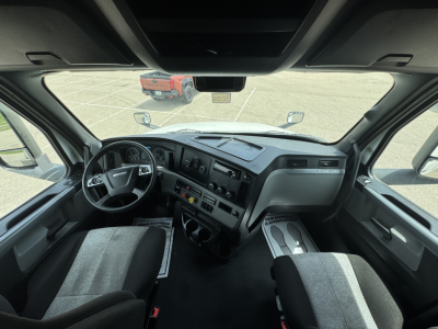 Freightliner Cascadia 126 cab interior showing steering wheel and dashboard with gauges and center controls.
