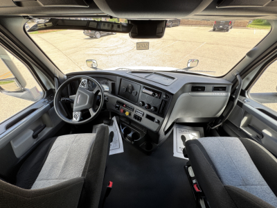 Cab interior of a 2021 Freightliner Cascadia 126 conventional sleeper showing steering wheel, dashboard, and front seats.