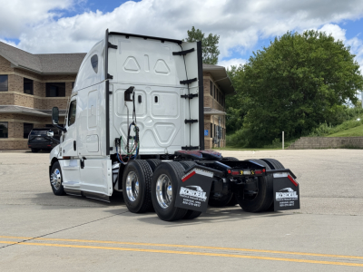Freightliner Cascadia 126 tractor rear view showing dual rear axles and fifth wheel, white exterior, glossy mirrors, back of sleeper cab.