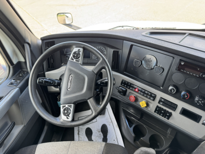Truck cabin interior showing steering wheel with control stalks, dashboard gauges, and center console with buttons; no legible serials or labels visible.