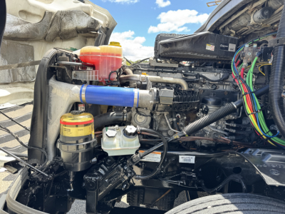 Freightliner Cascadia engine bay showing coolant reservoir and various hoses and wiring.