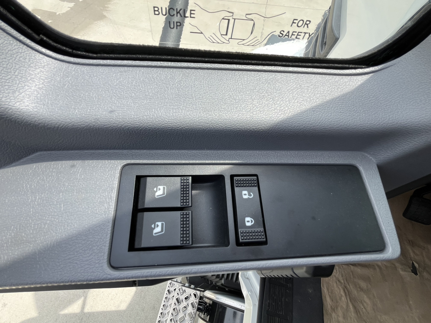 Cab door controls panel inside a Mack MD7 showing window/lock switches and door handle area.