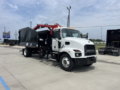 Mack MD7 truck with grapple body in a dealership lot showing white cab and red grapple arm attached to black dump body.