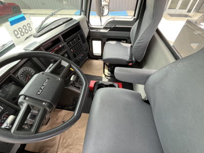 Mack MD7 cab interior showing steering wheel and driver's seat with dashboard controls and center console.