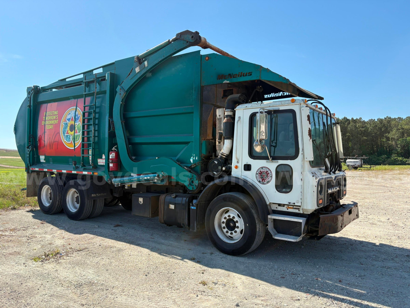 Garbage truck 2012 Mack MRU613 in-service showing garbage body and dumping mechanism.