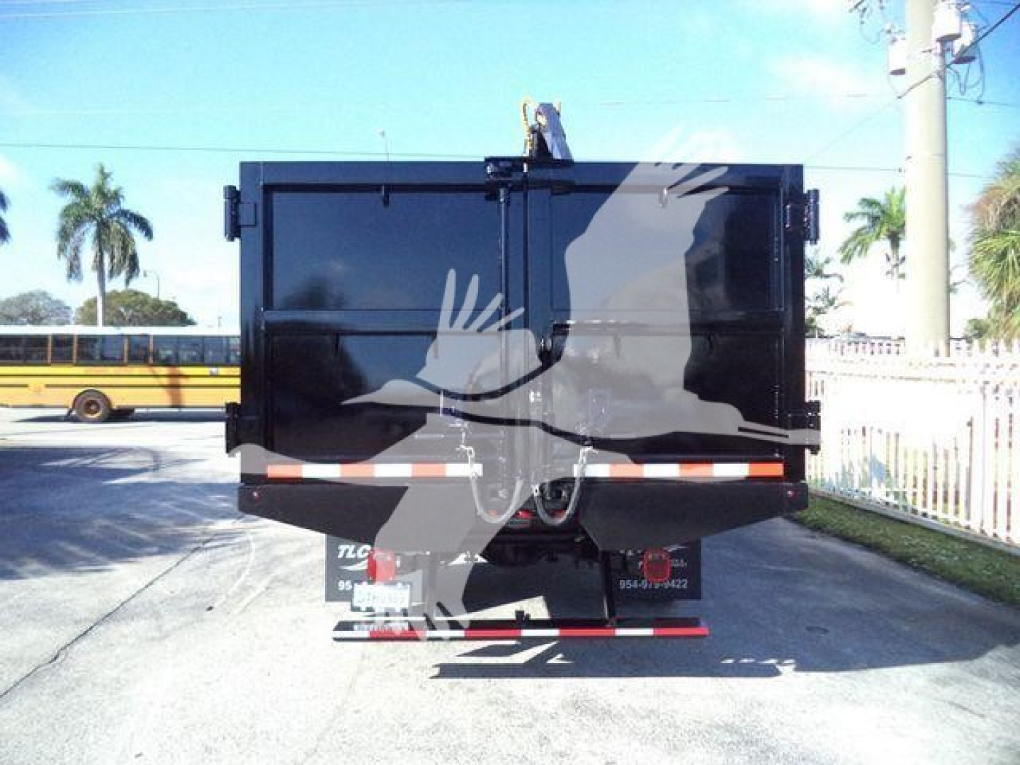 Back view of a black Chevrolet Silverado 6500HD dump truck with dual rear doors and reflective bar across the tailgate.
