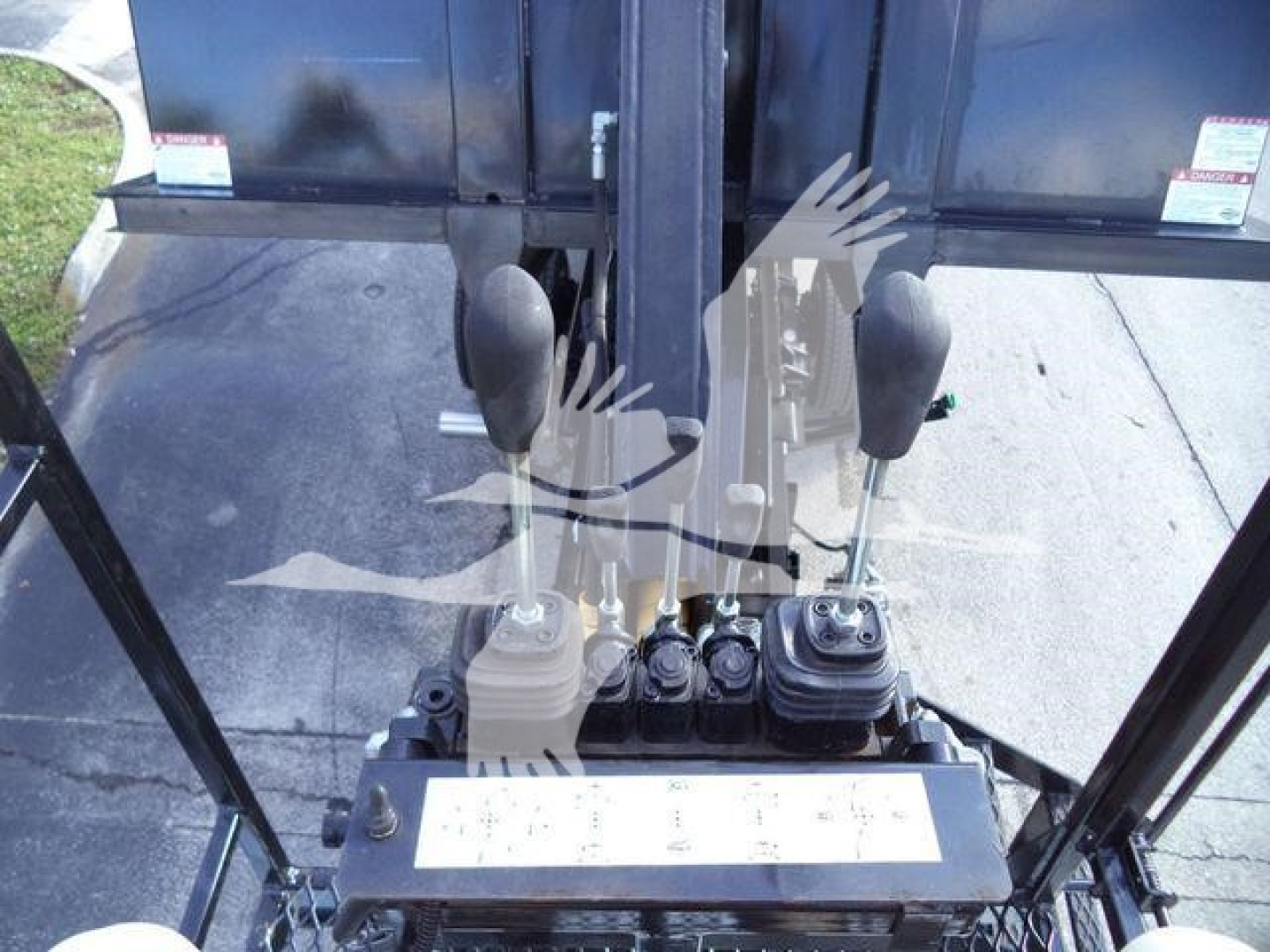 Front interior view of a 2023 Chevrolet Silverado 6500HD cab with two joystick levers and control panel, black spill-proof console, hydraulic controls, and protective cab frame.