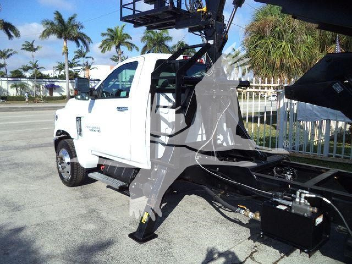 Truck cab of a 2023 Chevrolet Silverado 6500HD with a mounted lifting arm and workspace in the bed area, front angled view
