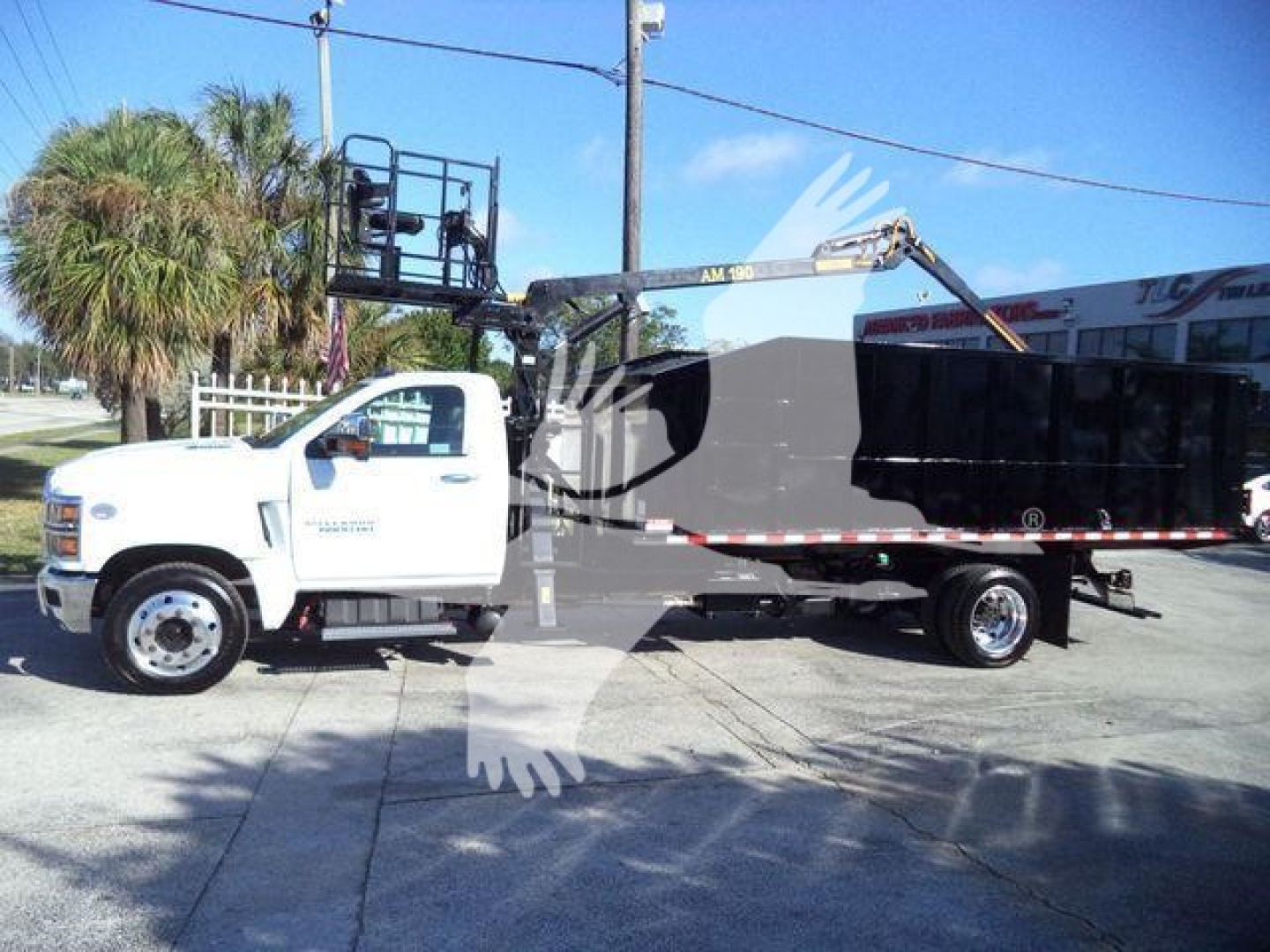 Truck cab of a 2023 Chevrolet Silverado 6500HD with a large dump bed and aerial lift equipment mounted on the bed, side view.