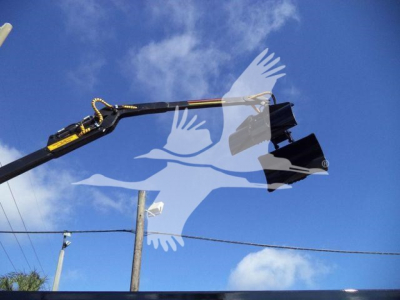 Front view of a 2023 Chevrolet Silverado 6500HD truck with crane attachment extended overhead; blue sky background.