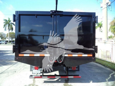 Back view of a 2023 Chevrolet Silverado 6500HD dump truck with rear doors closed and safety stripes, license plate frames visible.