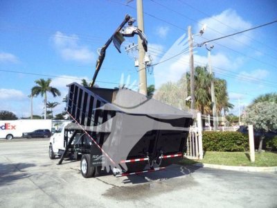 Truck bed with hydraulic dump in raised position on a Chevrolet Silverado 6500HD trailer chassis. Visible components include the dump bed, hydraulic arm, and rear wheels.