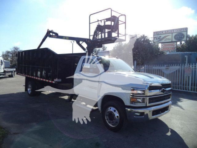 Chevrolet Silverado 6500HD new truck with a bucket lift on a white cab and black dump bed, visible signage in background.