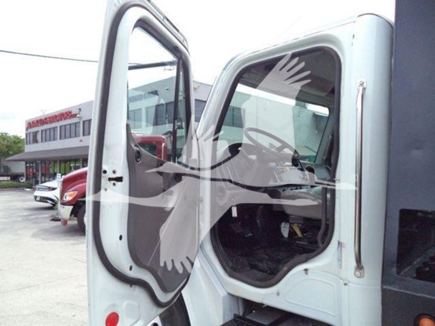 Truck cab open door of Freightliner Business Class M2 106 rollback showing interior dashboard and door frame with side mirror.