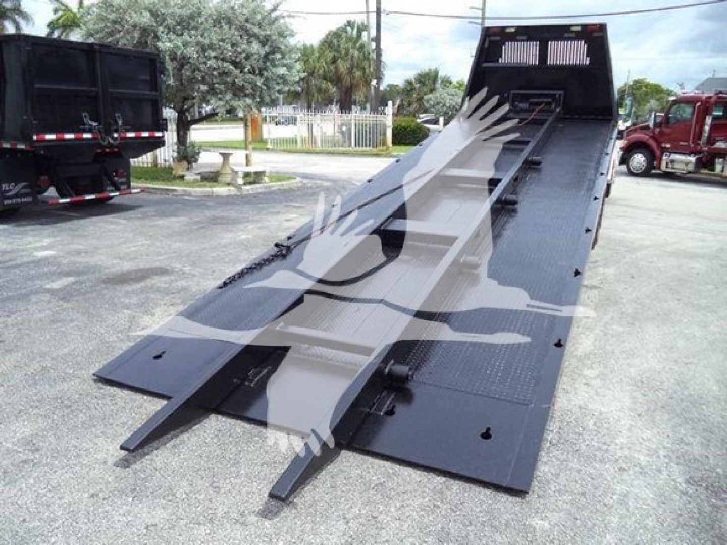 Truck bed with a raised flatbed incline and wheel-lift ramps, black metal surface, Freightliner M2 106 rollback equipment visible.