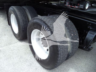 Dual rear axles with white rims and heavy-duty tires on a Freightliner truck chassis; visible are dual tires, wheel rims, and suspension components.
