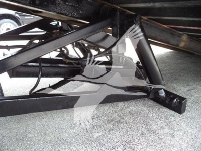 Tractor-trailer chassis components visible under a Freightliner Business Class M2 106 rollback. Metal frame with hydraulic lines and hitch area in view.