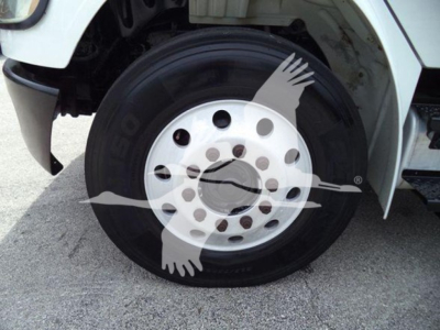 Truck wheel close-up showing steel rim with black tire and white fender, Freightliner M2 roll-off vehicle context.