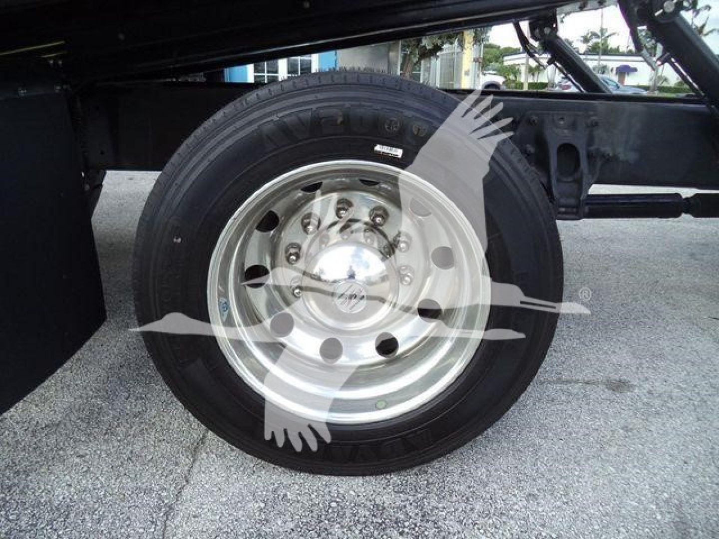 Truck wheel and tire close-up showing a chrome steel wheel with lug nuts under a Peterbilt 337 rollback chassis