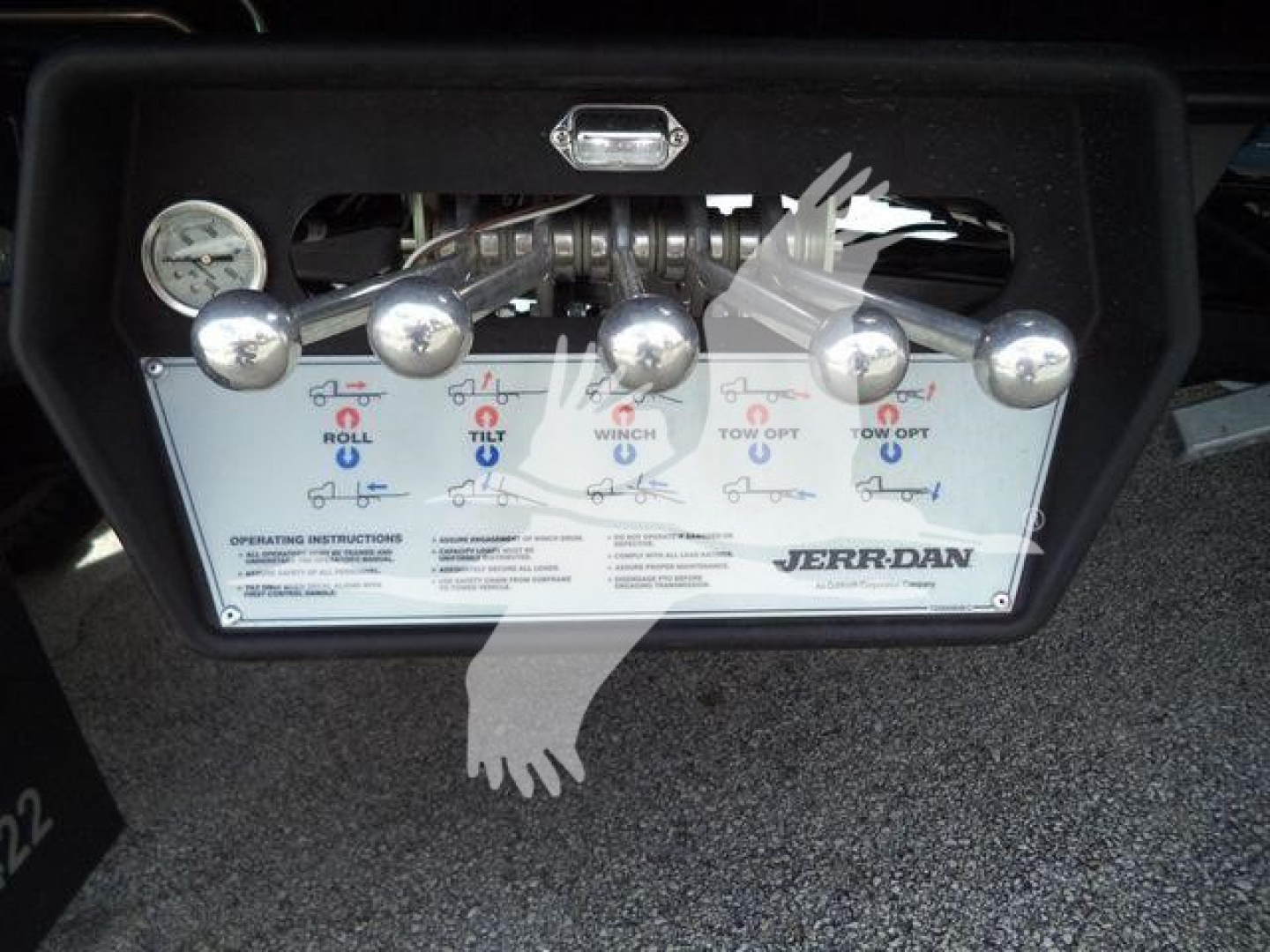 Panel with multiple control levers and gauges on a Peterbilt rollback truck; labels show incline/tilt control levers and a Jerr-Dan branding plate.