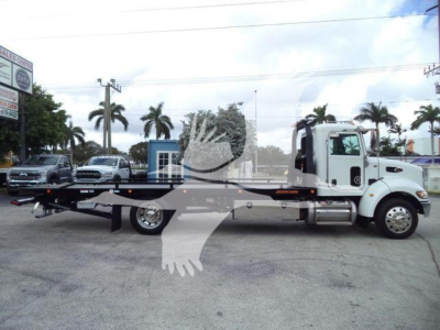 Truck bed rollback wrecker on 2019 Peterbilt 337 in-service view showing side profile and flatbed equipment.