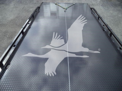 Truck bed with diamond plate surface and an overhead hoist, showing a white flying gull logo on the metal deck.