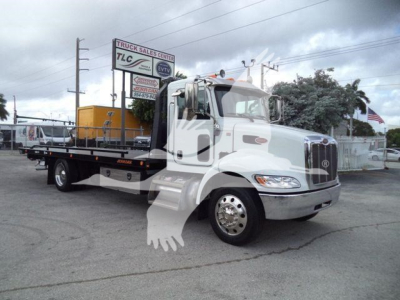 Peterbilt 337 rollback truck in white with flatbed at dealership, stock number T99359FM, factory cab and dual rear wheels visible.