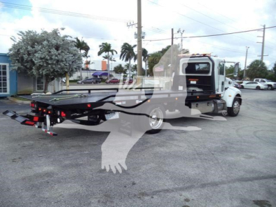 Peterbilt 337 rollback tow truck rear view showing hydraulic tilt bed and tethered wheel chocks.