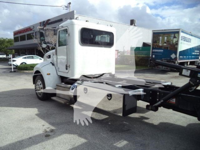 Peterbilt 337 rollback truck side view showing cab and chassis frame with hook-lift system and white cab.