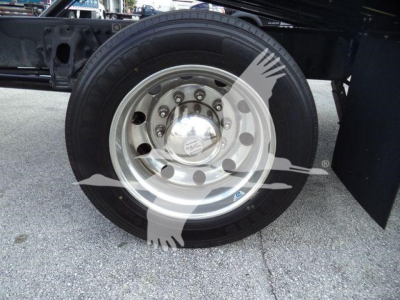 Wheel and tire of a Peterbilt 337 rollback truck showing chrome hubcap and black tire.