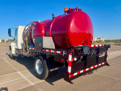 Vacuum tank truck rear and side view showing red cylindrical tank, white cab, and reflective safety stripes.
