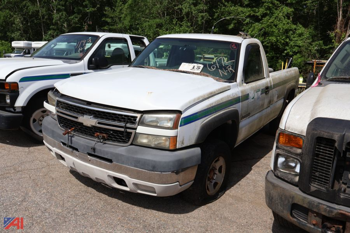 Chevrolet Silverado 2500HD pickup truck in a used lot, front-left view with white body and blue-green stripe details