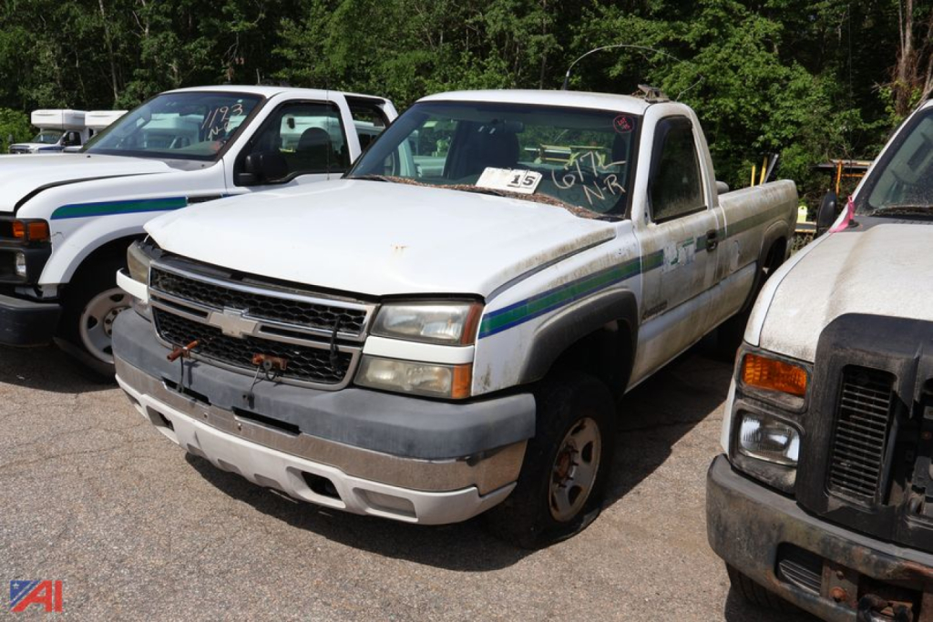 Chevrolet Silverado 2500HD pickup truck in a used lot, front-left view with white body and blue-green stripe details