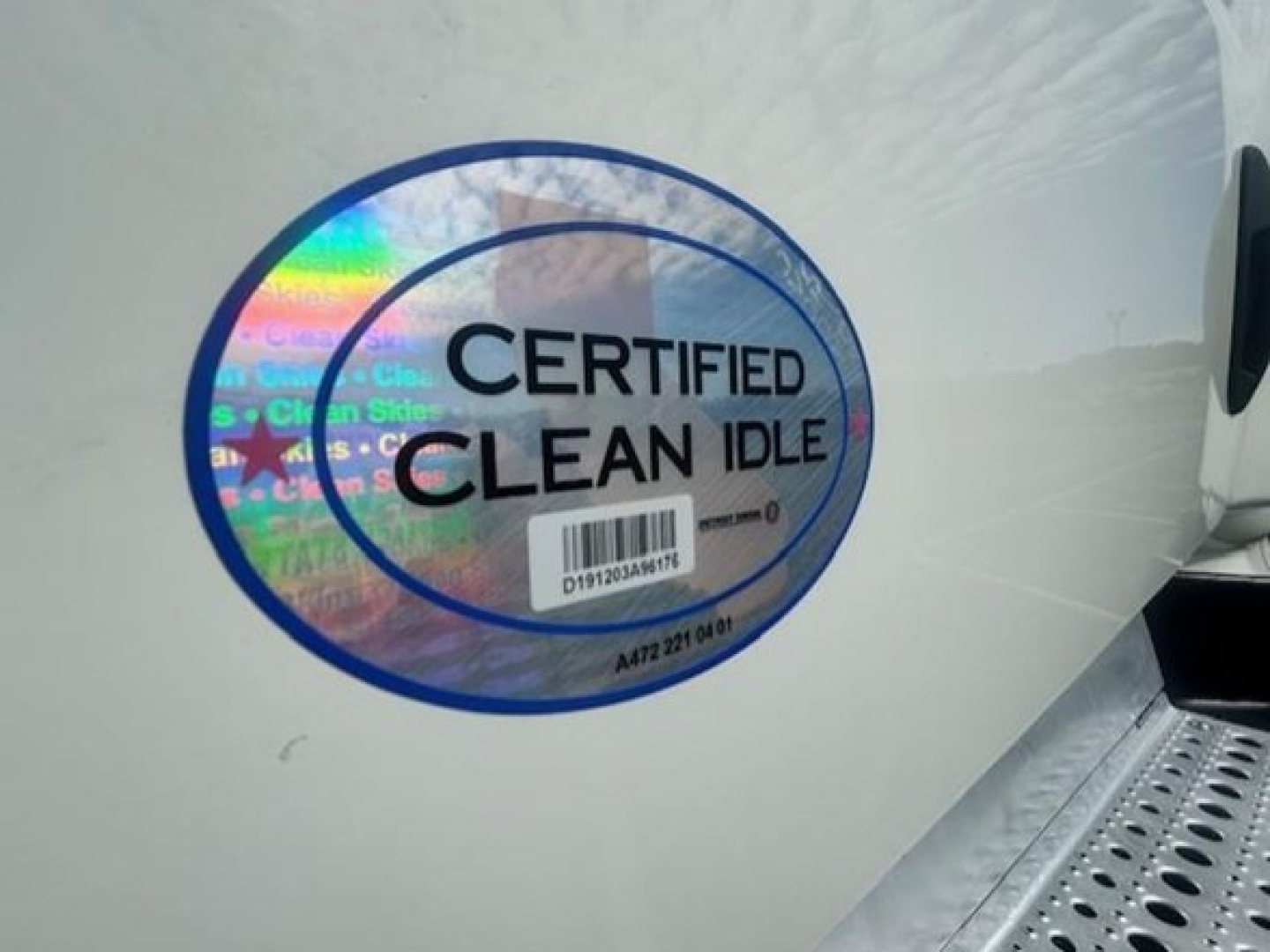 Freightliner Cascadia 116 side door area showing CERTIFIED CLEAN IDLE sticker on light-colored body.