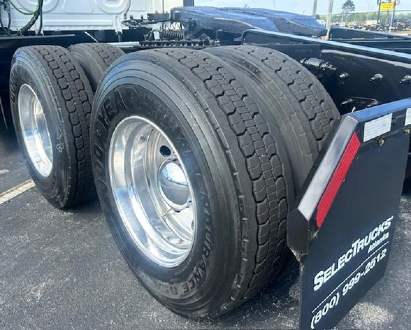 Dual rear axles with Goodyear tires and chrome wheels on a Freightliner Cascadia 116 tractor, visible mudflap with 'SELECT TRUCKS' branding.