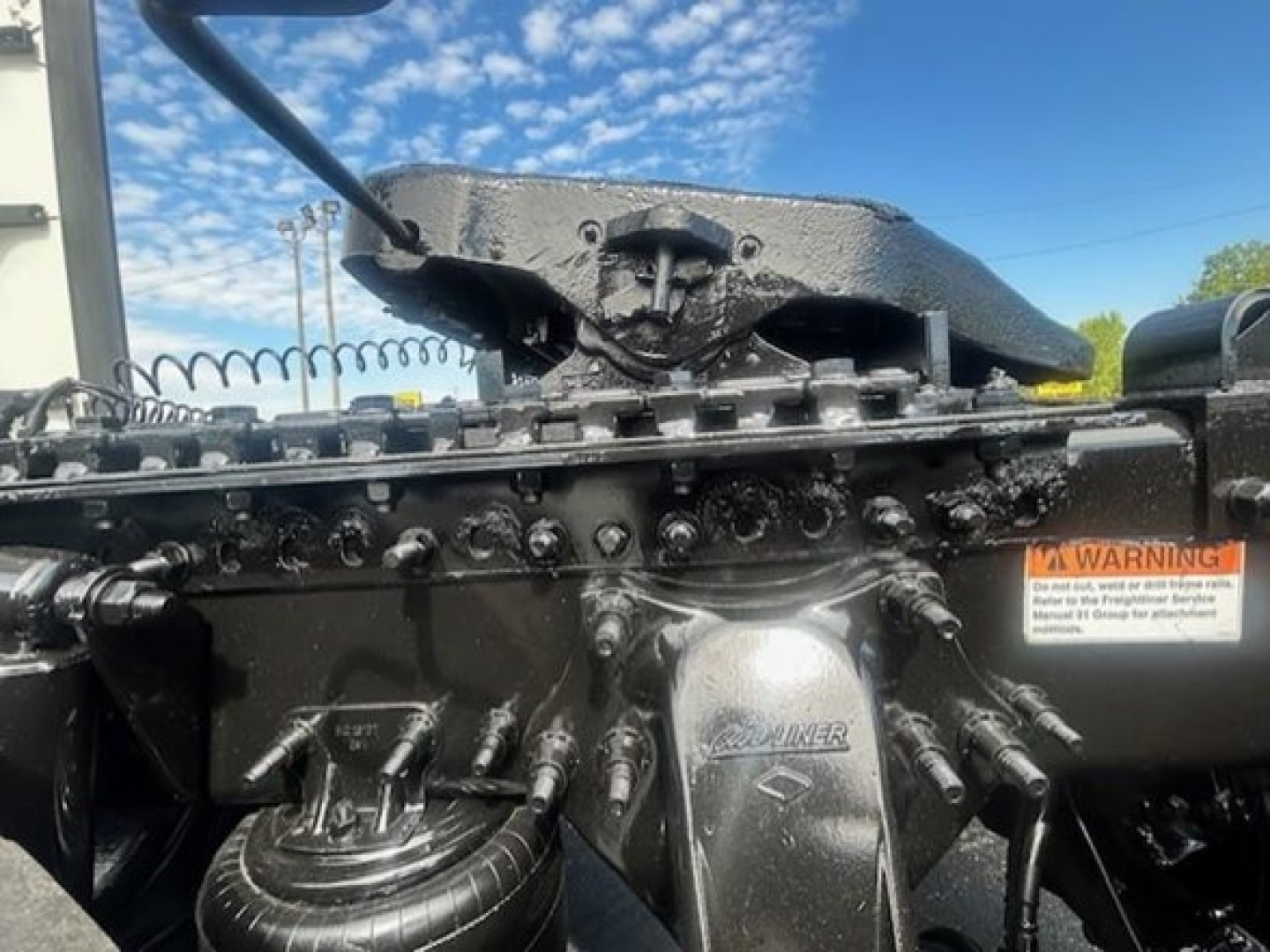 Truck engine bay showing Freightliner Cascadia 116 front with cooled engine components and hoses labeled, warning sticker visible.